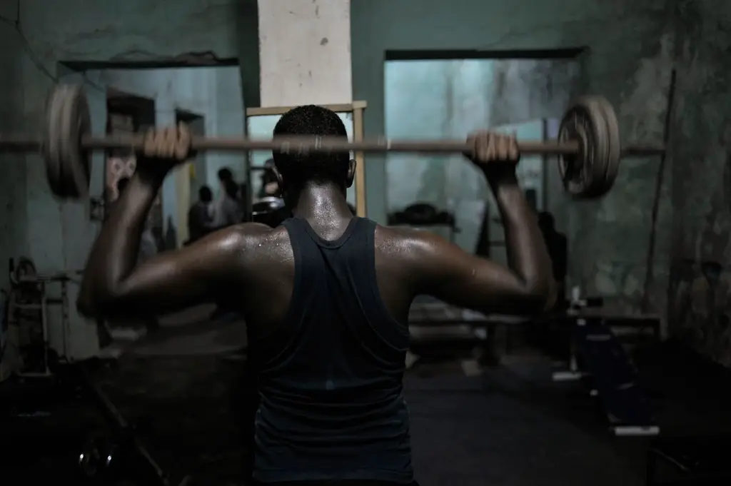 A lifter seen from behind holding a loaded barbell overhead